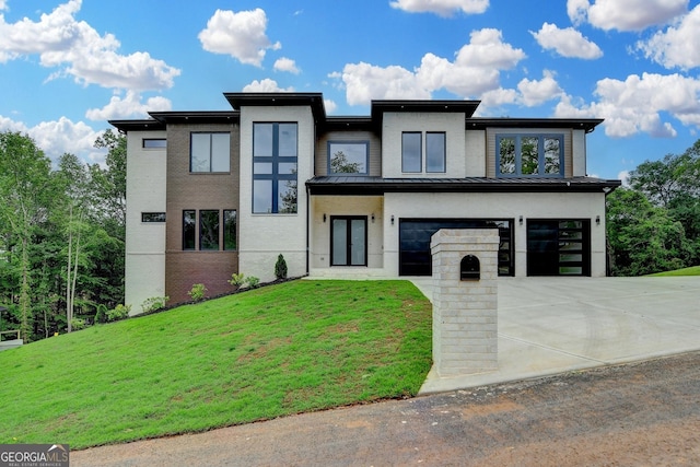 modern home featuring an attached garage, driveway, stucco siding, a front yard, and a standing seam roof