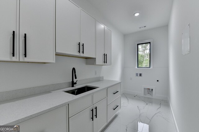 kitchen with a sink, white cabinetry, baseboards, and marble finish floor