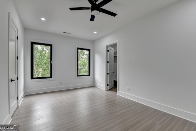 unfurnished bedroom with wood finished floors, a ceiling fan, visible vents, baseboards, and recessed lighting