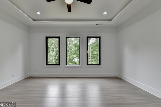 empty room featuring a raised ceiling, a wealth of natural light, and visible vents