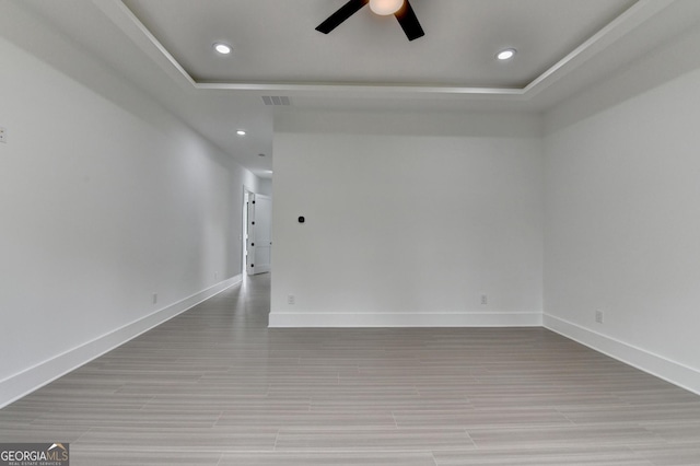 spare room with light wood-type flooring, baseboards, a raised ceiling, ceiling fan, and recessed lighting