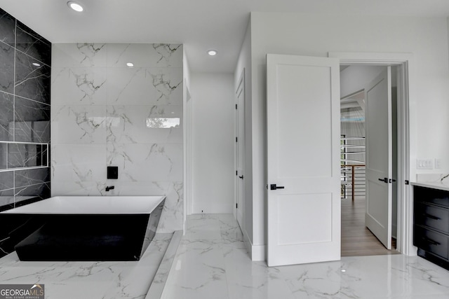 bathroom with marble finish floor, a freestanding tub, and recessed lighting