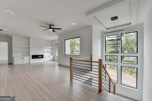 unfurnished living room with wood finished floors, attic access, recessed lighting, a ceiling fan, and baseboards