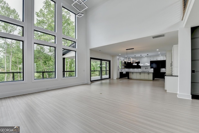 unfurnished living room with a high ceiling, baseboards, and visible vents