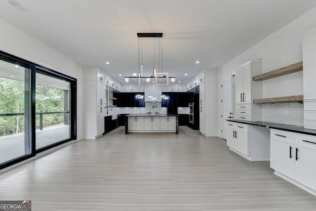 kitchen featuring a center island, open shelves, dark countertops, light wood-type flooring, and tasteful backsplash