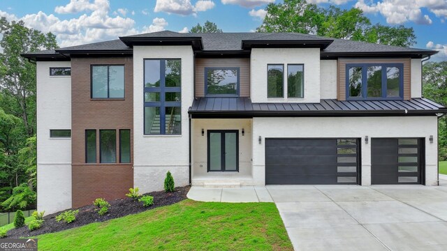 view of front facade featuring a garage, concrete driveway, a front yard, brick siding, and a standing seam roof
