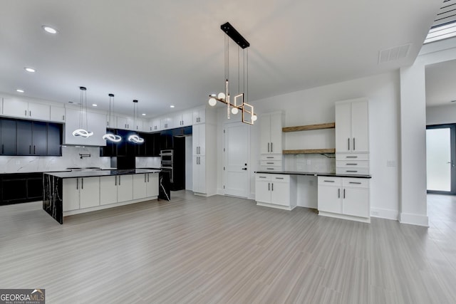 kitchen featuring oven, backsplash, dark countertops, and visible vents