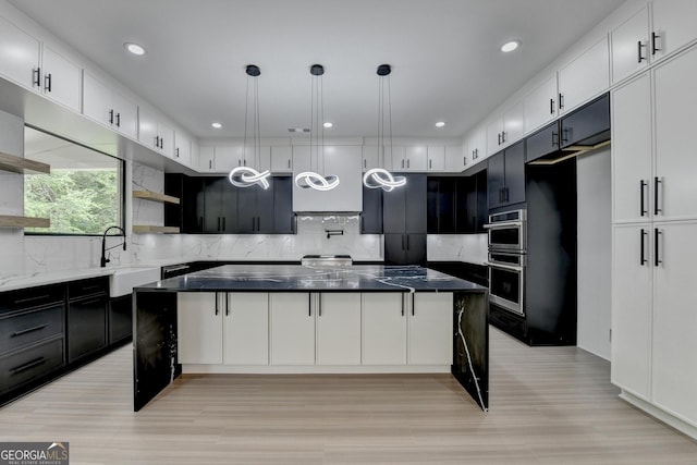 kitchen with a sink, light wood finished floors, open shelves, and decorative backsplash