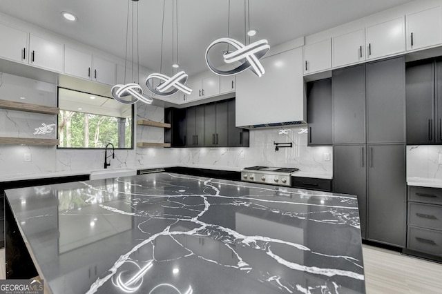 kitchen featuring a sink, open shelves, tasteful backsplash, light stone counters, and recessed lighting