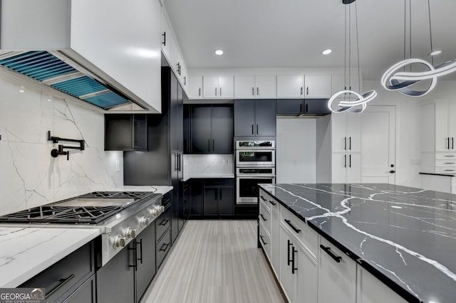 kitchen featuring white cabinets, premium range hood, appliances with stainless steel finishes, and dark stone counters