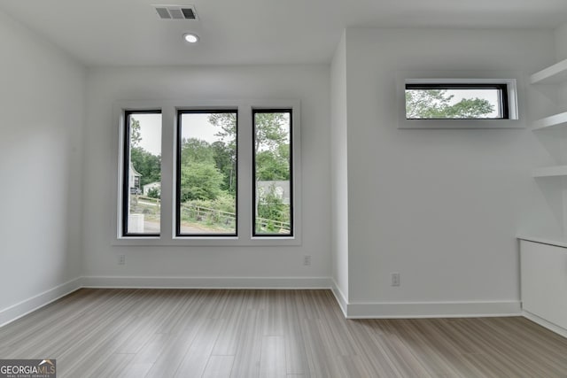 empty room featuring baseboards, a wealth of natural light, and visible vents