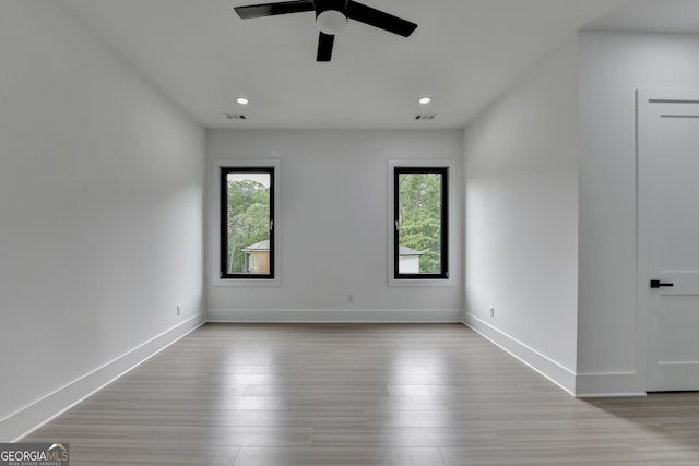 empty room with a ceiling fan, baseboards, visible vents, and wood finished floors