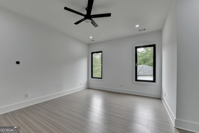 unfurnished room with a ceiling fan, baseboards, visible vents, and wood finished floors
