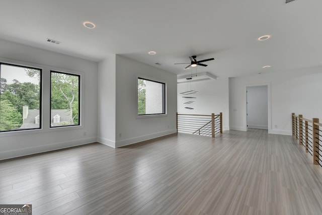 unfurnished living room with light wood finished floors, a wealth of natural light, baseboards, and visible vents