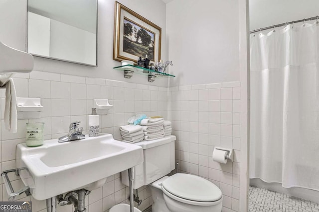 bathroom with toilet, a sink, a wainscoted wall, tile walls, and tile patterned flooring