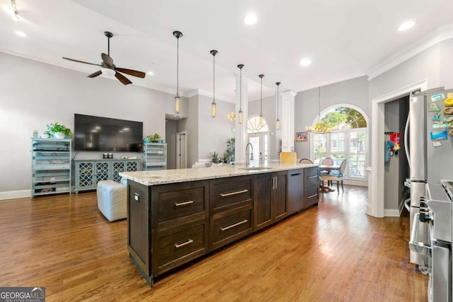kitchen with dark brown cabinets, wood finished floors, a sink, open floor plan, and ceiling fan
