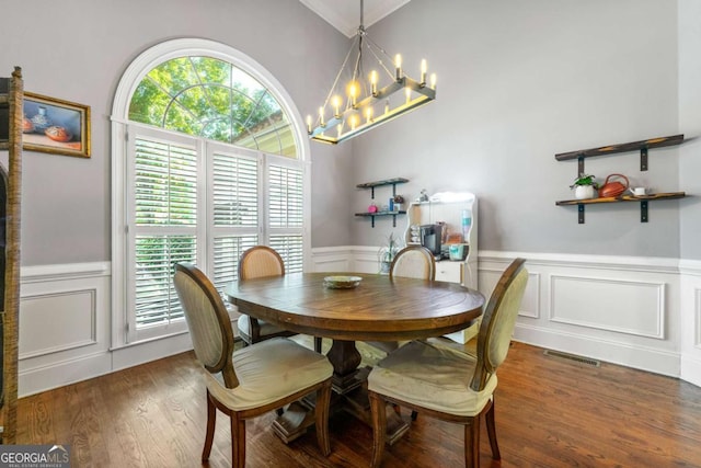 dining space with a chandelier, a decorative wall, a wainscoted wall, and wood finished floors