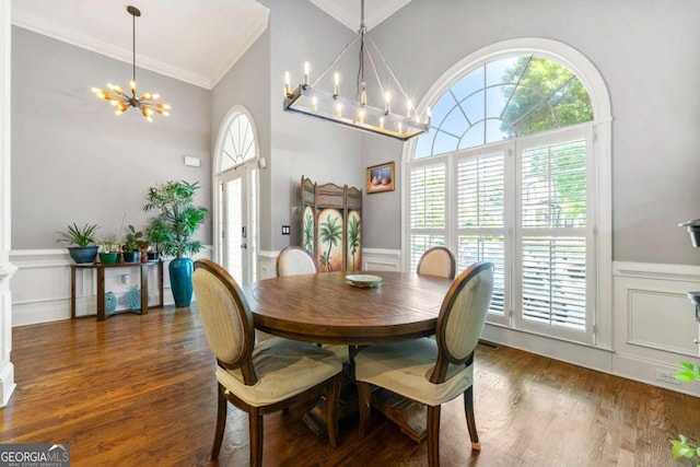 dining space featuring a decorative wall, a chandelier, crown molding, and wainscoting