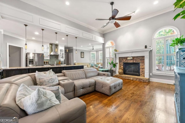 living room featuring wood finished floors, a ceiling fan, a stone fireplace, and recessed lighting