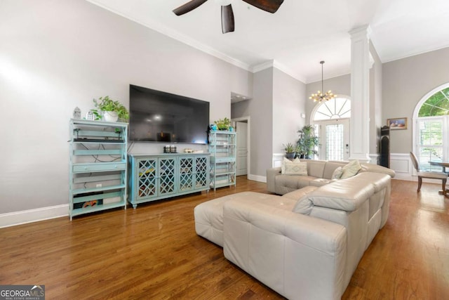living area featuring crown molding, ceiling fan with notable chandelier, baseboards, and wood finished floors