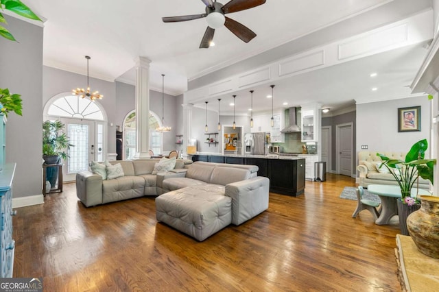 living room featuring crown molding, baseboards, wood finished floors, and ceiling fan with notable chandelier