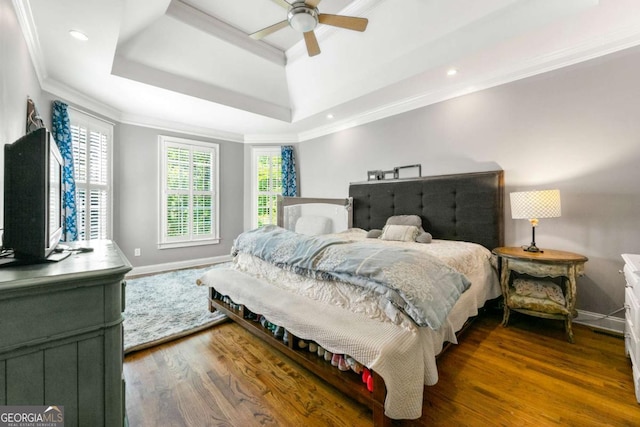 bedroom with a tray ceiling, ornamental molding, recessed lighting, and wood finished floors