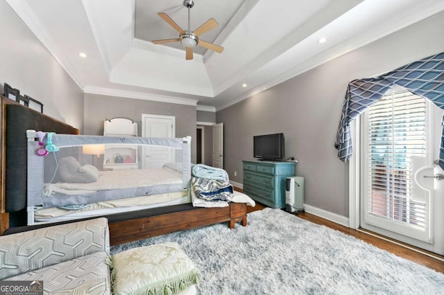 bedroom with wood finished floors, recessed lighting, crown molding, a tray ceiling, and baseboards