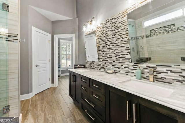 bathroom featuring a sink, backsplash, baseboards, and a shower stall