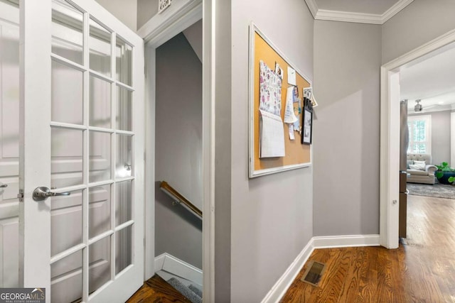 hall featuring baseboards, ornamental molding, visible vents, wood finished floors, and an upstairs landing
