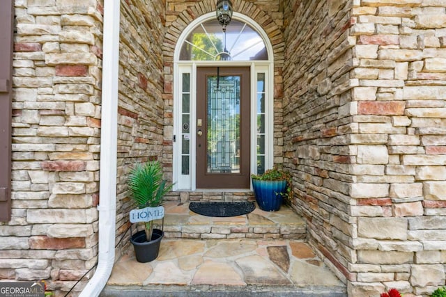 doorway to property with stone siding and brick siding