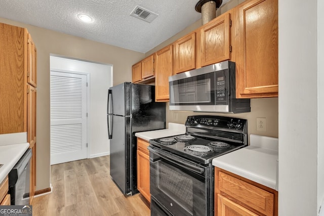 1750 Clairmont Rd Unit 32, Decatur, GA 30033 - kitchen featuring black appliances, light wood-style floors, light countertops, and a textured ceiling