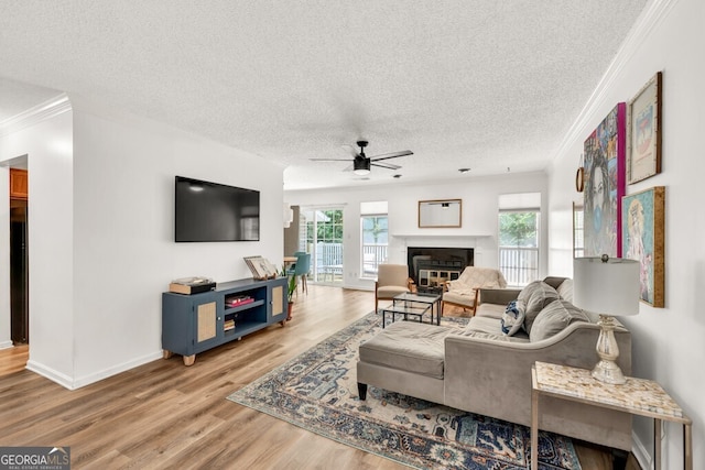 1750 Clairmont Rd Unit 32, Decatur, GA 30033 - living room featuring a ceiling fan, crown molding, a glass covered fireplace, wood finished floors, and a textured ceiling