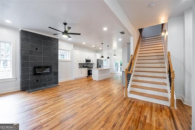 1120 Arlington Ave SW, Atlanta, GA 30310 - living area featuring visible vents, stairway, light wood finished floors, a ceiling fan, and a tiled fireplace