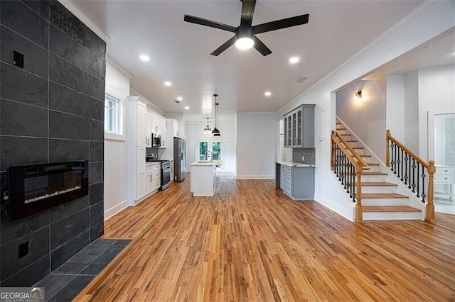 1120 Arlington Ave SW, Atlanta, GA 30310 - unfurnished living room with stairs, ornamental molding, light wood-type flooring, a fireplace, and a ceiling fan