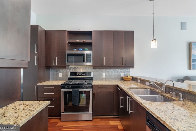 kitchen with dark brown cabinets, wood finished floors, a sink, stainless steel appliances, and backsplash