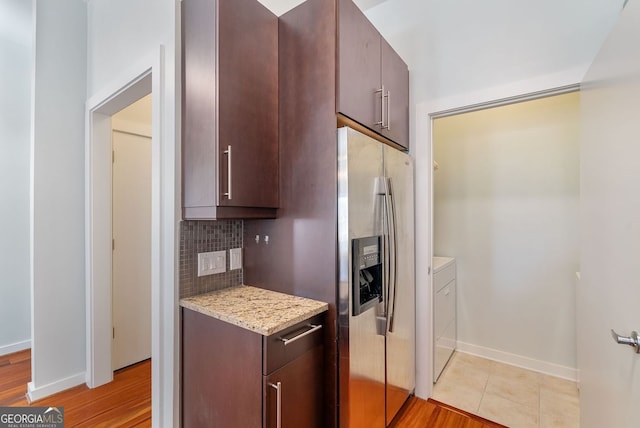 kitchen with stainless steel fridge, dark brown cabinetry, tasteful backsplash, independent washer and dryer, and light stone counters
