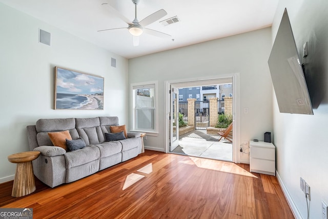 living room with ceiling fan, baseboards, visible vents, and wood finished floors