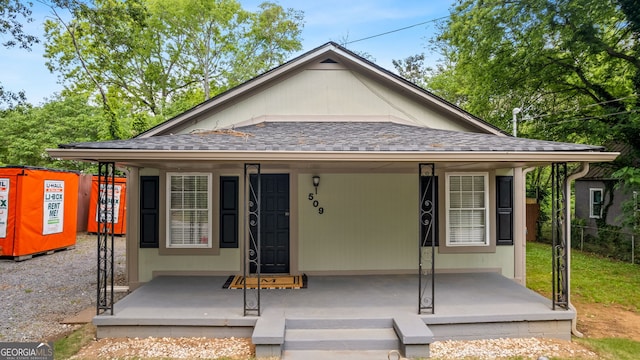 bungalow featuring a porch, roof with shingles, and fence