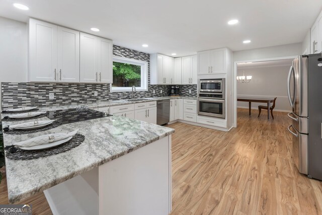 5830 Wilbanks Dr, Peachtree Corners, GA 30092 - kitchen featuring stainless steel appliances, a sink, light stone countertops, tasteful backsplash, and white cabinetry