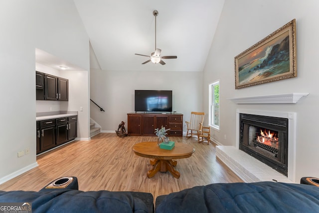 5830 Wilbanks Dr, Peachtree Corners, GA 30092 - living room featuring ceiling fan, stairway, light wood-style flooring, a lit fireplace, and high vaulted ceiling