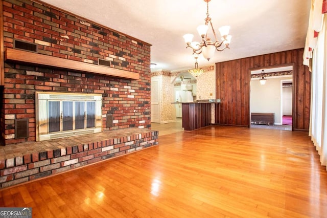 1181 Angelia Dr SW, Mableton, GA 30126 - unfurnished living room featuring a notable chandelier, a brick fireplace, and wood finished floors