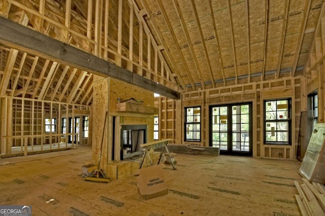 misc room featuring a fireplace with raised hearth and high vaulted ceiling