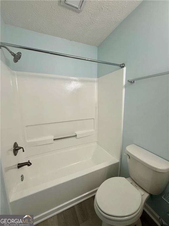 5075 Forest Downs Ln, Atlanta, GA 30349 - full bathroom featuring a textured ceiling, wood finished floors, toilet, and  shower combination