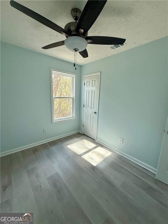 5075 Forest Downs Ln, Atlanta, GA 30349 - unfurnished bedroom featuring a ceiling fan, a closet, a textured ceiling, baseboards, and wood finished floors