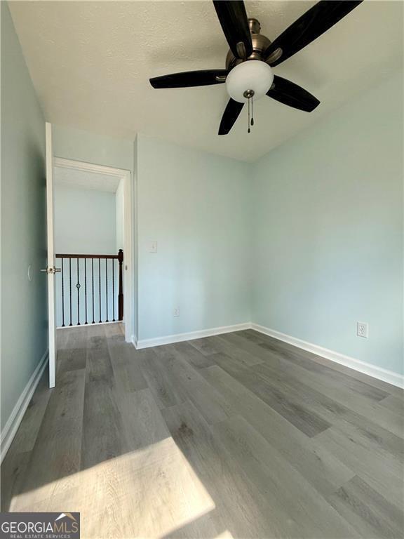 5075 Forest Downs Ln, Atlanta, GA 30349 - spare room featuring a ceiling fan, wood finished floors, and baseboards
