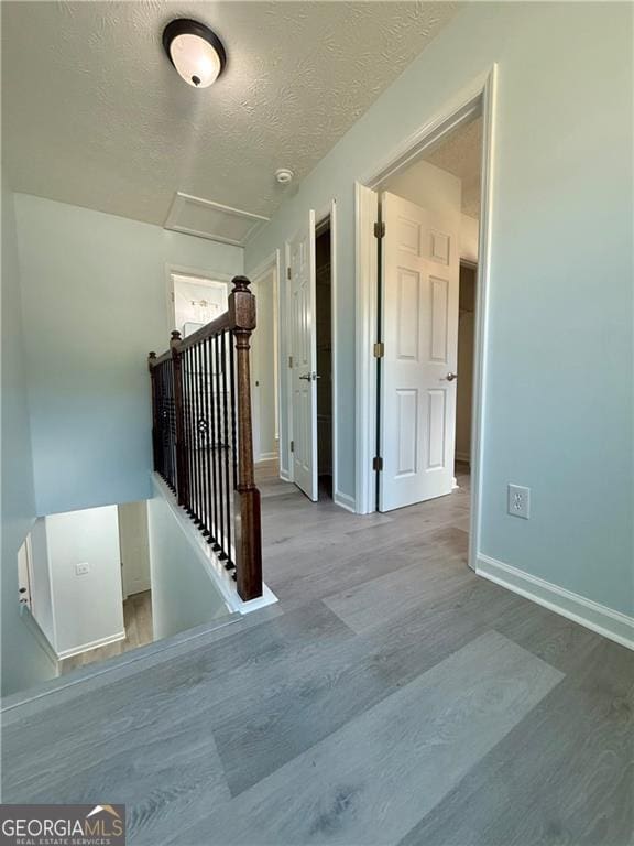 5075 Forest Downs Ln, Atlanta, GA 30349 - interior space featuring wood finished floors, a textured ceiling, attic access, an upstairs landing, and baseboards