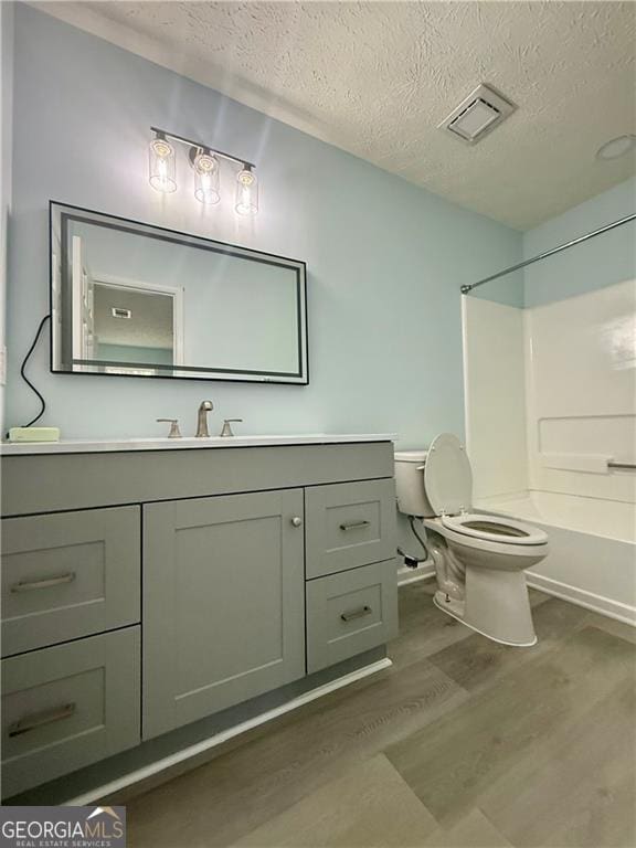 5075 Forest Downs Ln, Atlanta, GA 30349 - bathroom with toilet, wood finished floors, vanity, a textured ceiling, and visible vents