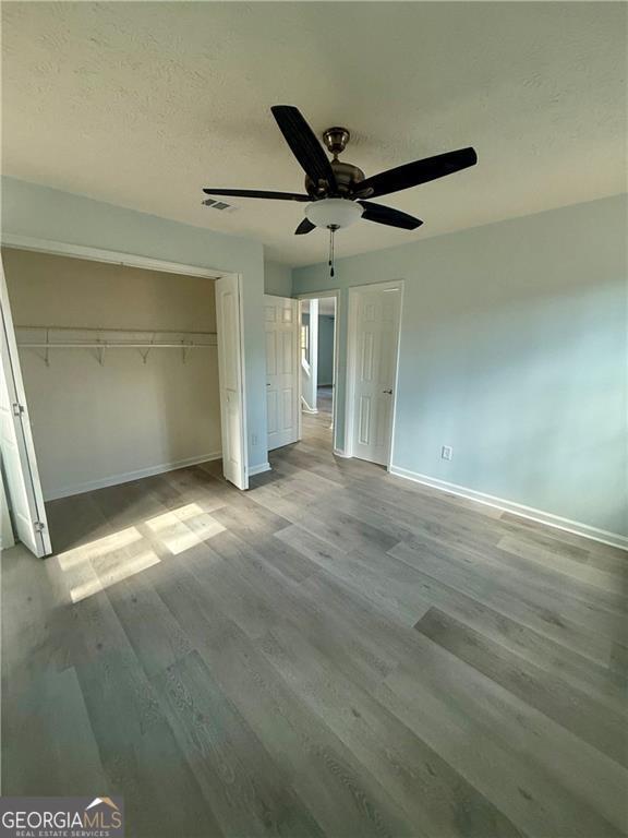 5075 Forest Downs Ln, Atlanta, GA 30349 - unfurnished bedroom with baseboards, a closet, visible vents, and wood finished floors