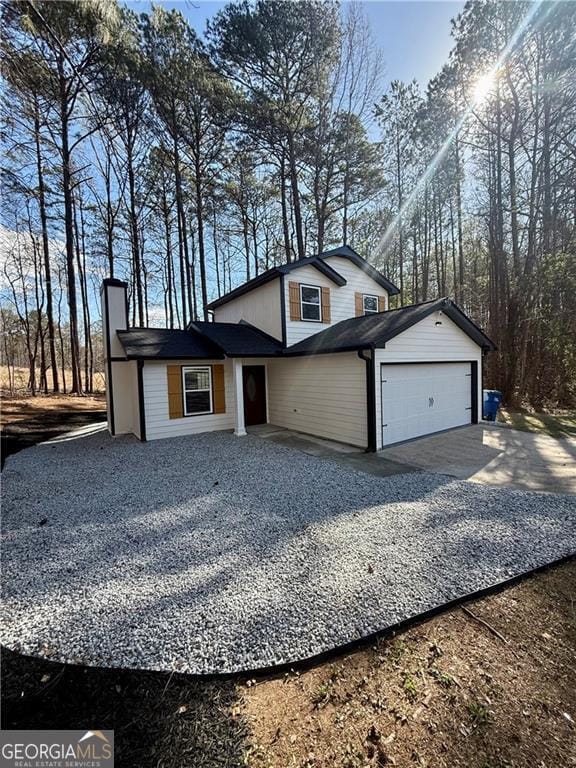 5075 Forest Downs Ln, Atlanta, GA 30349 - view of front of property featuring gravel driveway, a chimney, and an attached garage