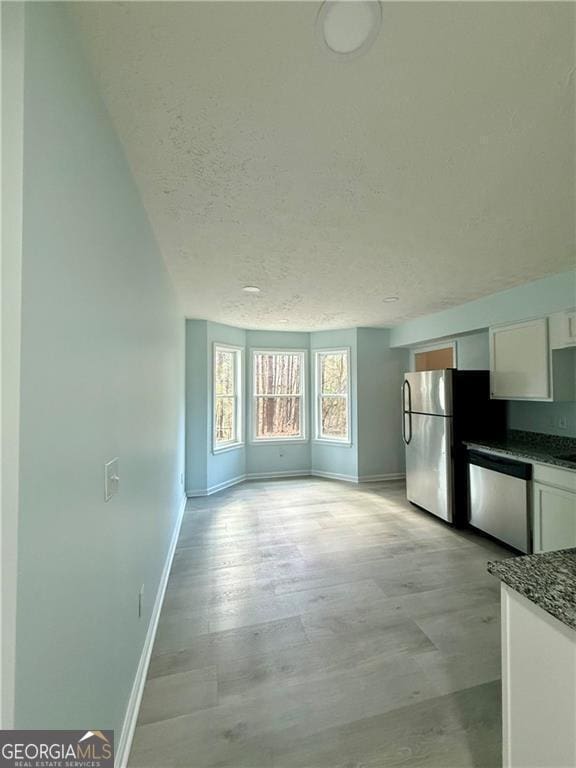 5075 Forest Downs Ln, Atlanta, GA 30349 - unfurnished living room featuring a textured ceiling, baseboards, and light wood-style flooring